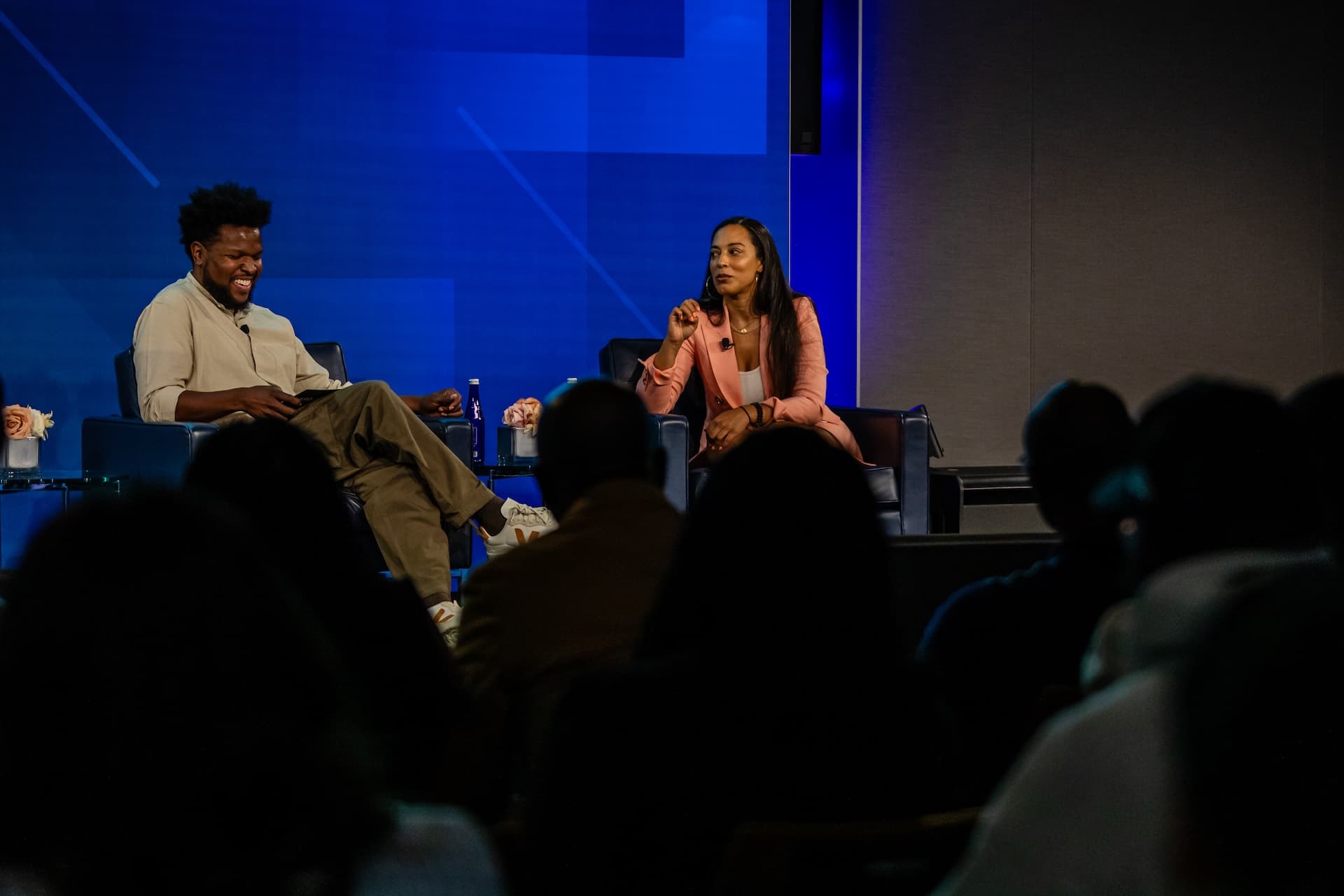 Will Lucas seated on stage interviewing a guest under blue stage lighting at AfroTech Newark 2024.