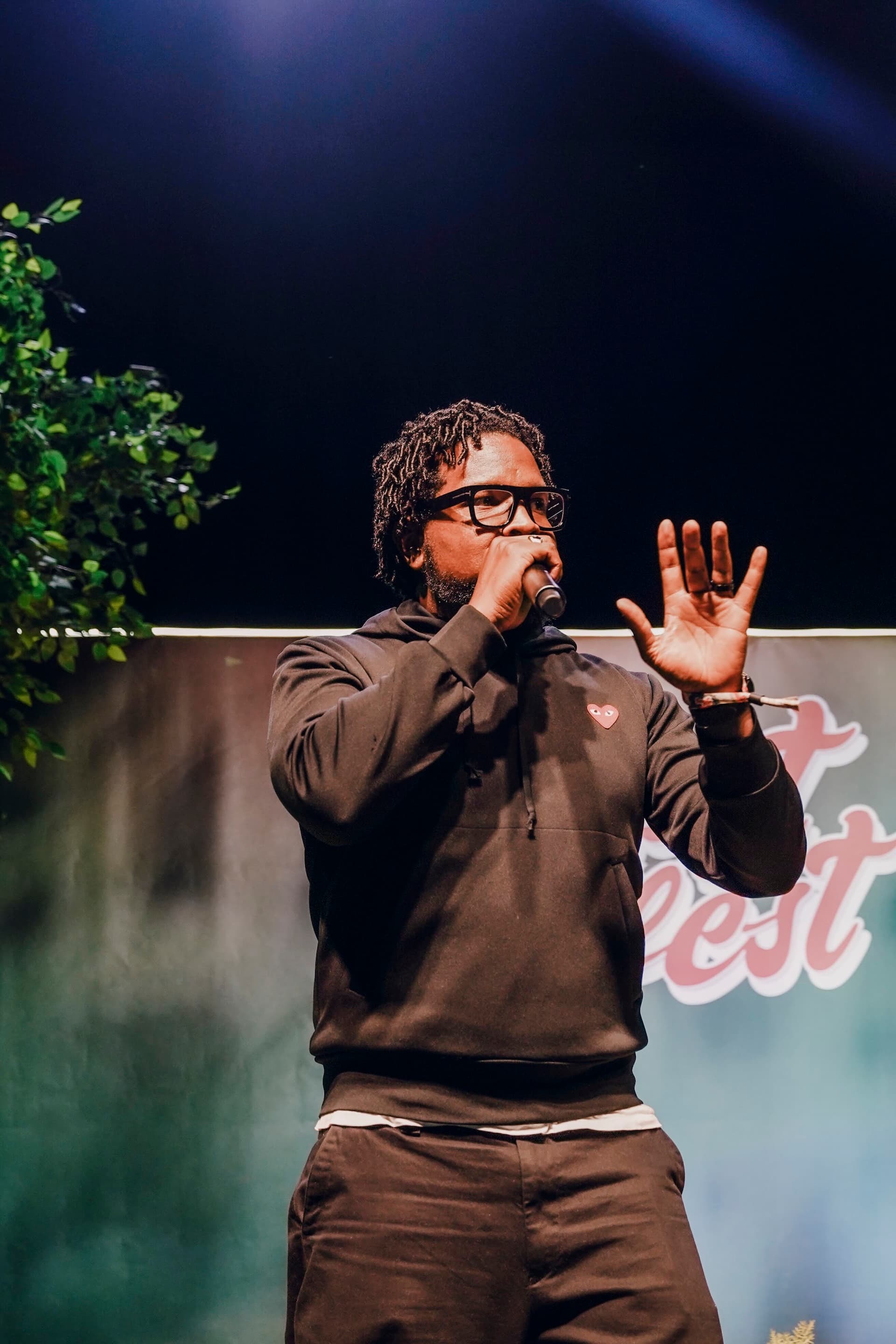 Will Lucas on stage in a hoodie, microphone in hand mid-sentence.