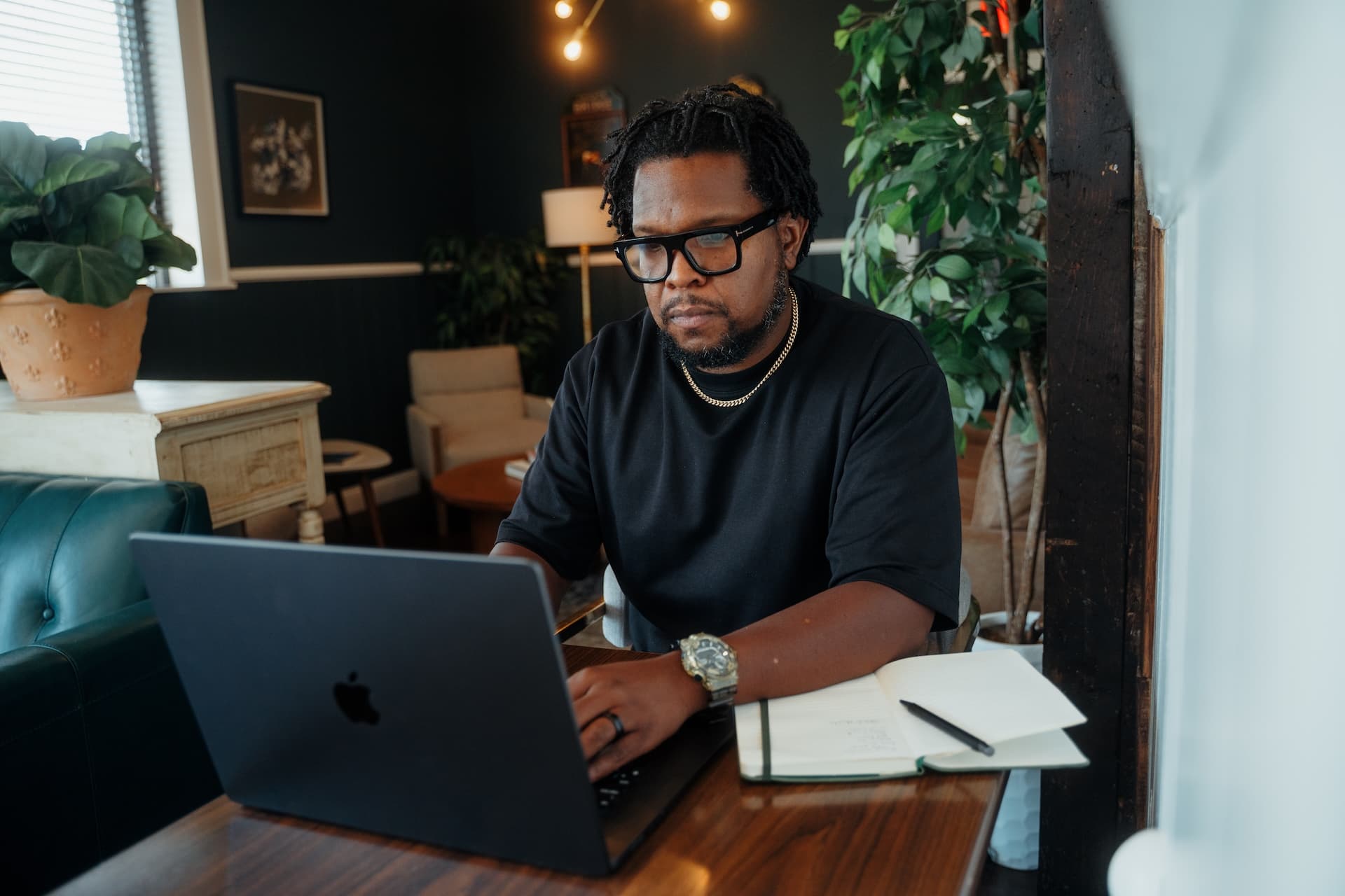 Will Lucas working at a wooden desk on a MacBook in a warm interior.